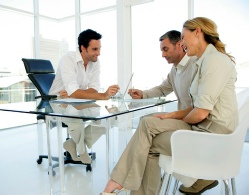 3 people around table signing a contract